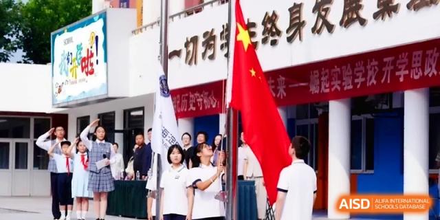 Students participate in a flag-raising ceremony, standing respectfully as the national flag is hoisted on campus at the Beijing Haidian Rising Experimental School