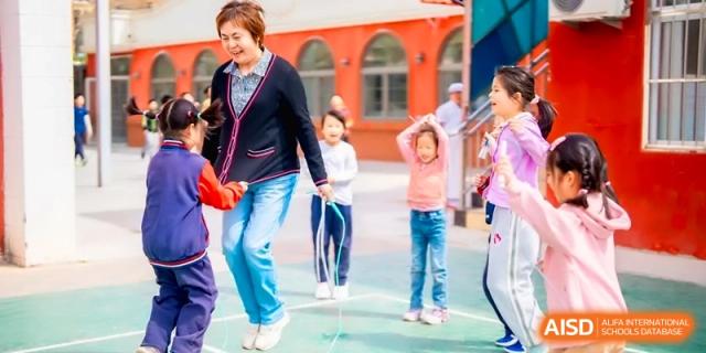 A teacher and students enjoy a fun jump rope session together on the colorful school playground at the Beijing Haidian Rising Experimental School