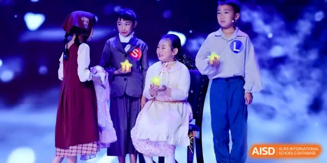 Three students in formal costumes perform on a dark stage with bright lights during a school theater production at Beijing Haidian Rising Experimental School