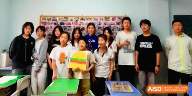A group of students posing together in front of a collage of photos during a school event at HD Beijing School.