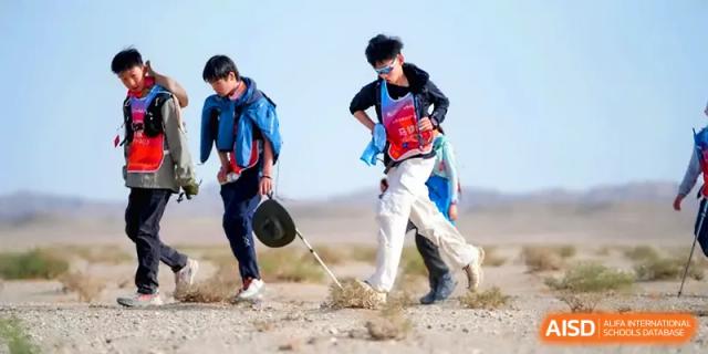 Two young hikers navigating a sandy trail while carrying backpacks during an outdoor adventure at HD Beijing School.