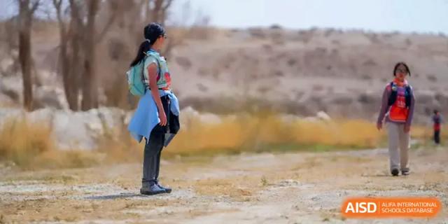 A student standing alone and looking out over a vast desert landscape during a school trekking expedition at HD Beijing School.