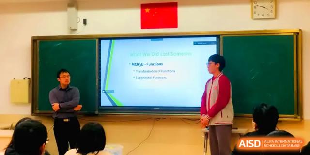A student stands next to a digital screen presenting a lesson on mathematical functions at Qingdao Experimental High School.