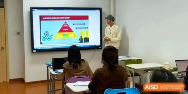 A student gives a presentation using a digital screen displaying a colorful pyramid chart at Qingdao Experimental High School.