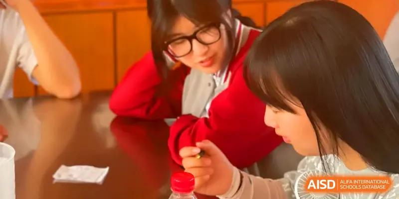 Two students collaborate closely on a project while sitting at a table in a classroom at Qingdao Experimental High School.