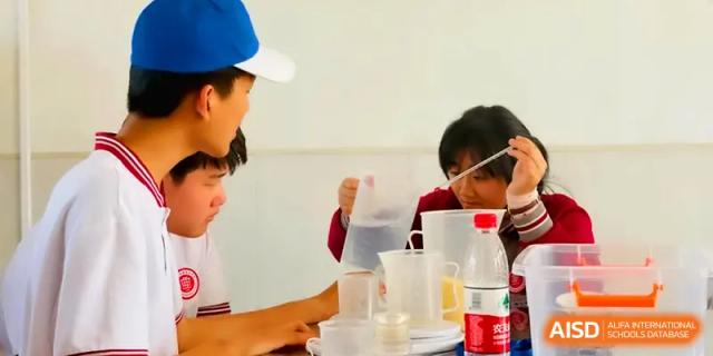 Students gather around a table to conduct a science experiment with water and pitchers at Qingdao Experimental High School.