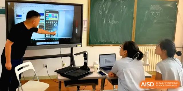 A student works at a desk equipped with a laptop and a digital screen showing a calculator at Qingdao Experimental High School.