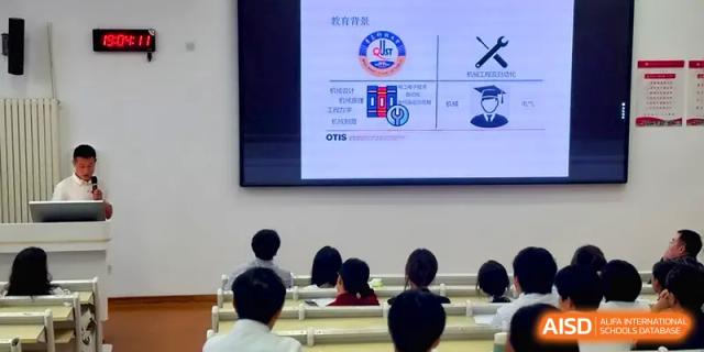 Students sit in a lecture hall facing a large presentation screen displaying diagrams at Qingdao Experimental High School.