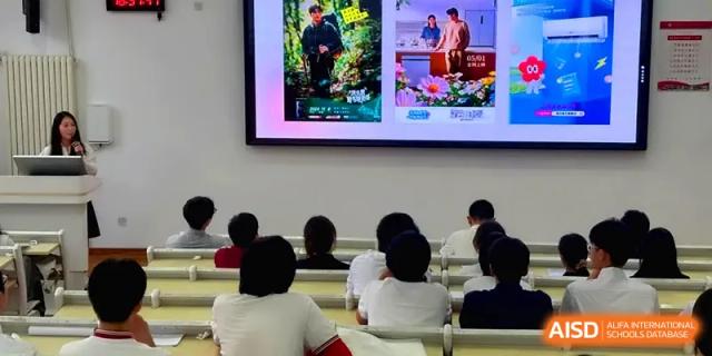 Students watch a video presentation on a large monitor in a brightly lit classroom at Qingdao Experimental High School.