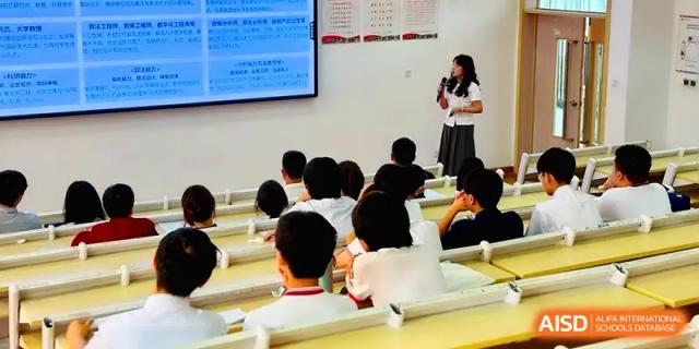 A female instructor presents a lesson to a seated group of students in a lecture hall at Qingdao Experimental High School.