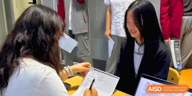 Close-up of a student and teacher collaborating on a written assignment in class at Qingdao Experimental High School.