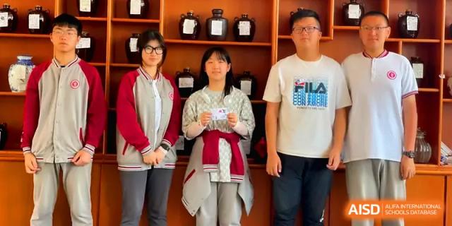 Three students stand together in front of a wooden shelf for a group photo at Qingdao Experimental High School.
