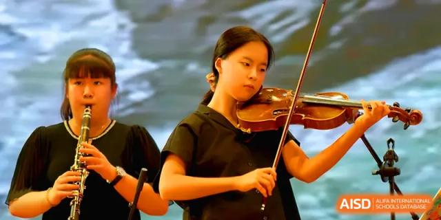 A young female student plays the violin with focus during a musical performance at Qingdao Experimental High School.
