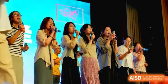 A group of female students perform a vocal piece together on a lighted stage at Qingdao Experimental High School.