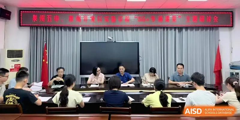 Educators sit at a long conference table facing a large digital screen during a formal academic planning or training session at Quanzhou No. 5 Middle School.
