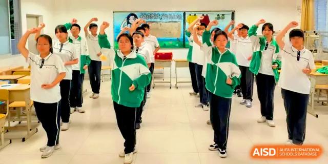 Students in green tracksuits perform synchronized physical exercises in a bright school hallway at Quanzhou No. 5 Middle School.