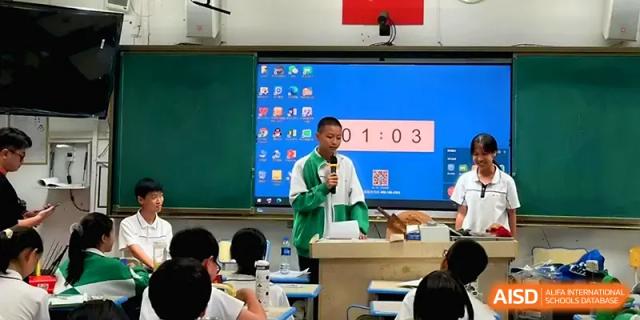 A student stands at a podium giving a presentation in front of a digital display in a modern classroom at Quanzhou No. 5 Middle School.