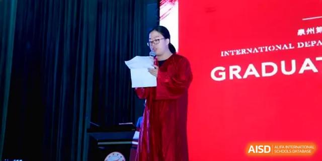 A student representative in a red academic gown reads a speech during a formal graduation event at Quanzhou No. 5 Middle School.