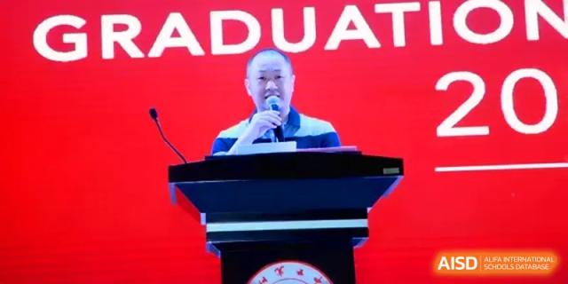 A school official gives an inspiring speech from a podium during a formal graduation ceremony at Quanzhou No. 5 Middle School.