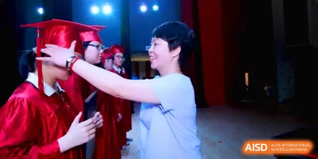 A teacher smiles while presenting a diploma to a graduating student during a formal indoor ceremony at Quanzhou No. 5 Middle School.