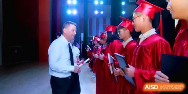 School leadership hands out certificates to a line of students in red graduation gowns during a ceremony at Quanzhou No. 5 Middle School.