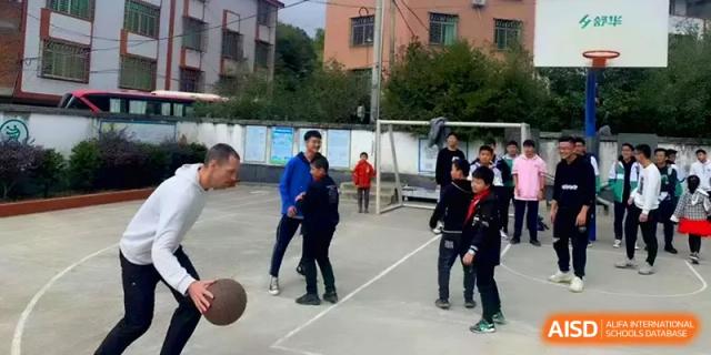 A teacher instructs students on basketball techniques during an outdoor physical education class at Quanzhou No. 5 Middle School.