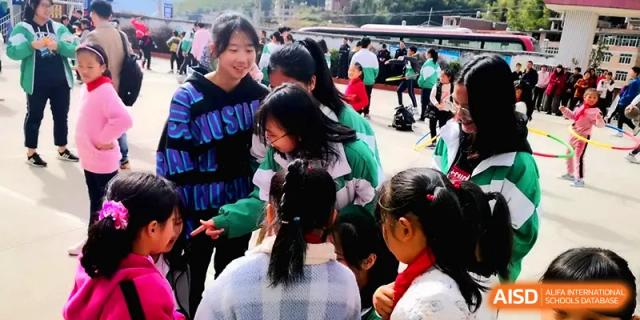 Students smiling and interacting during an outdoor school event, wearing casual and athletic attire at Quanzhou No. 5 Middle School.