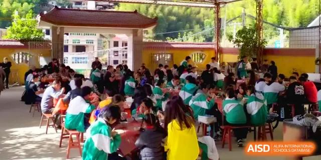 A large group of students in green and white uniforms gathered for an outdoor meal or social activity at Quanzhou No. 5 Middle School.