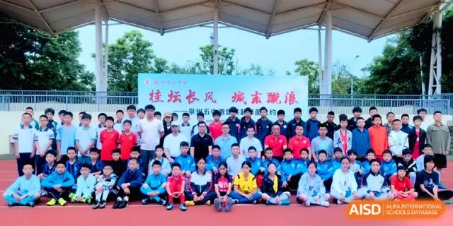 A large group of students and teachers in sports gear pose for a commemorative photo on the athletic field at Quanzhou No. 5 Middle School.