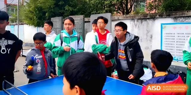 Students watching a table tennis match or outdoor game on the campus grounds during a break at Quanzhou No. 5 Middle School.