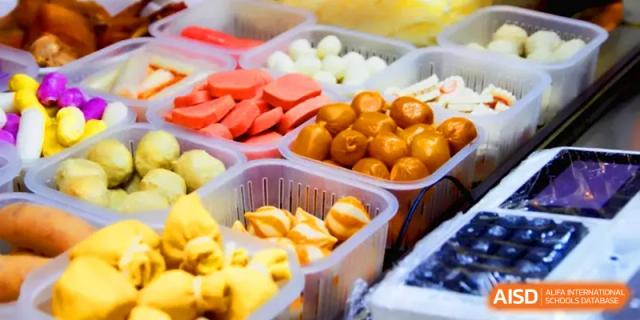 Various containers of snacks and street food items, including sausages and dumplings, at Quanzhou No. 5 Middle School.