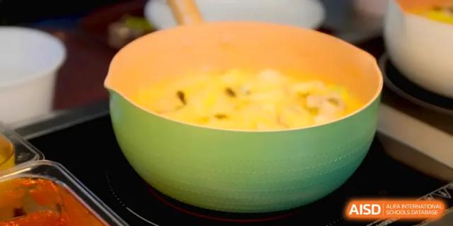 A light green pot of creamy soup or porridge being prepared for a nutritious student meal at Quanzhou No. 5 Middle School.
