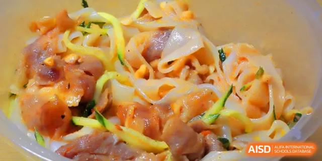 A close-up of a noodle dish with fresh vegetables prepared for a student meal at Quanzhou No. 5 Middle School.