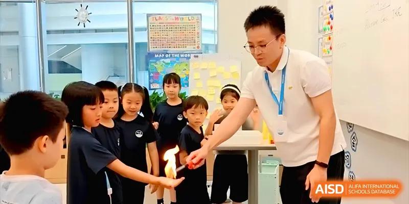 A science teacher demonstrates a controlled fire experiment to a group of curious young students at Shenzhen Mingwan School.