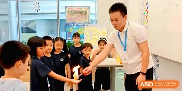 A science teacher demonstrates a controlled fire experiment to a group of curious young students at Shenzhen Mingwan School.