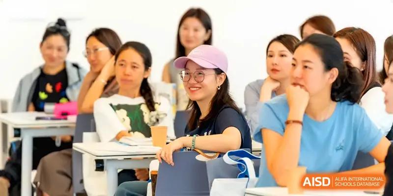 A group of adults sits in a lecture hall listening to a presentation during an event at Shenzhen Mingwan School.