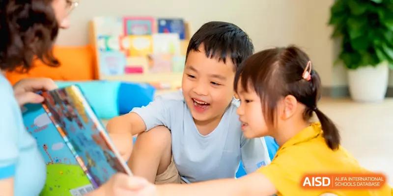 Two happy children laughing while sharing a book together in a colorful library at Shenzhen Mingwan School.