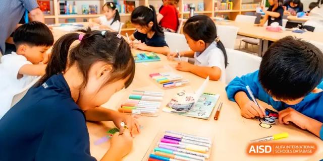 Young students sitting at a desk and drawing with colorful markers in an art class at Shenzhen Mingwan School.