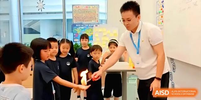 A science teacher performing a fire experiment for a group of curious elementary students at Shenzhen Mingwan School.