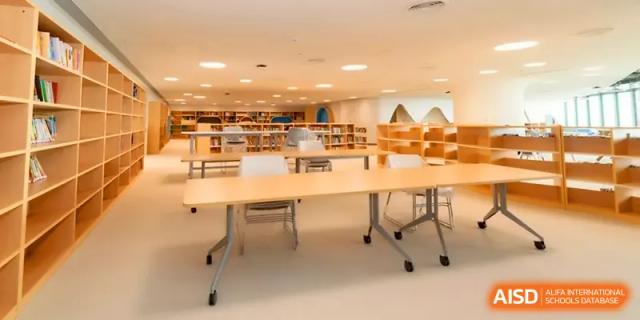 A spacious study hall featuring long tables and plenty of natural light for students at Shenzhen Mingwan School.