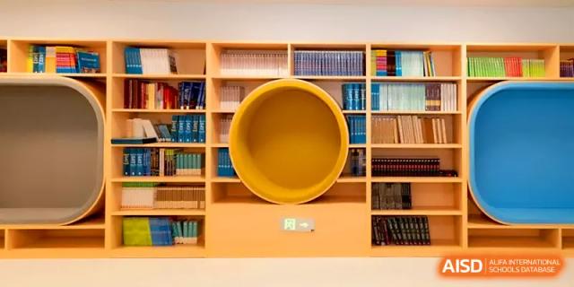A unique circular reading pod built into a large library bookshelf for quiet study at Shenzhen Mingwan School.