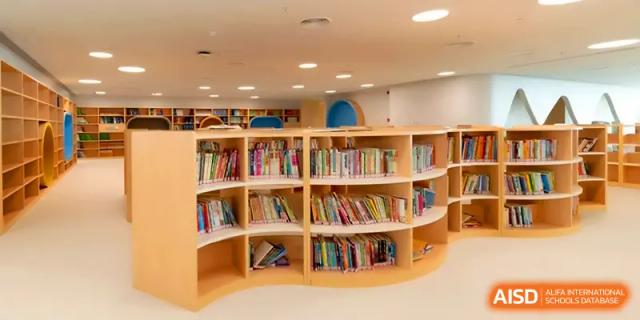 A curved, wooden bookshelf filled with diverse children's books in a cozy reading nook at Shenzhen Mingwan School.
