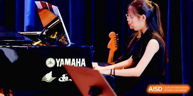 A student focused on playing a Yamaha keyboard during a music rehearsal session at Shenzhen Mingwan School.