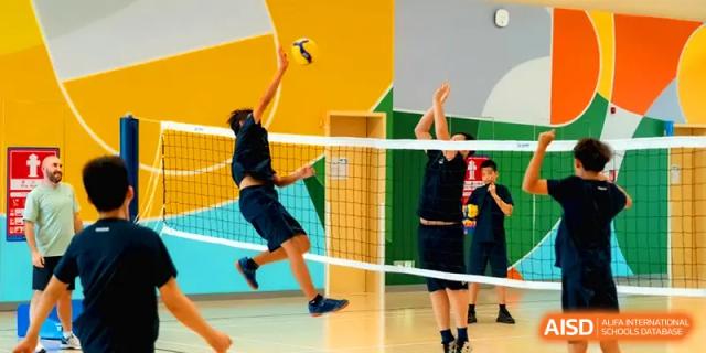 A student jumps high to spike a volleyball over the net during an indoor game at Shenzhen Mingwan School.
