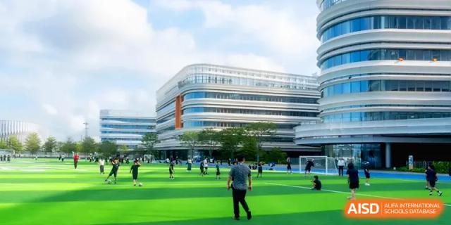 Overview of students and staff on the large green field in front of the modern campus building at Shenzhen Mingwan School.