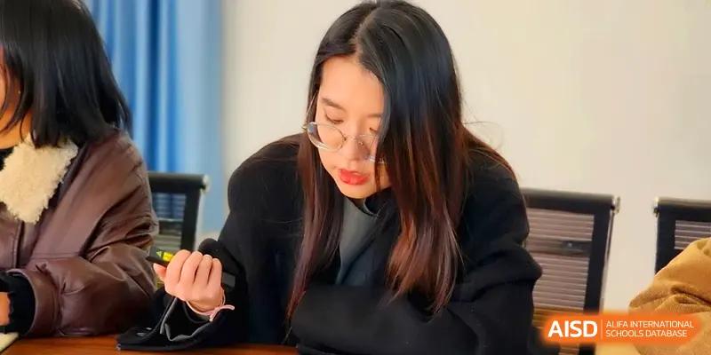 A teacher wearing glasses focuses on her work during a staff meeting session at The Guandu Experimental School Affiliated To Shanghai Normal University.