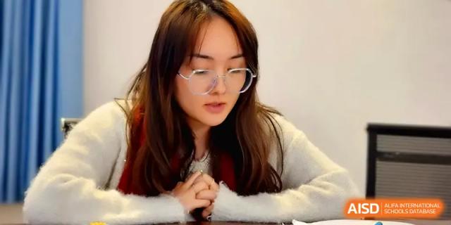 A young woman with glasses listens intently during a focused academic meeting at The Guandu Experimental School Affiliated To Shanghai Normal University.