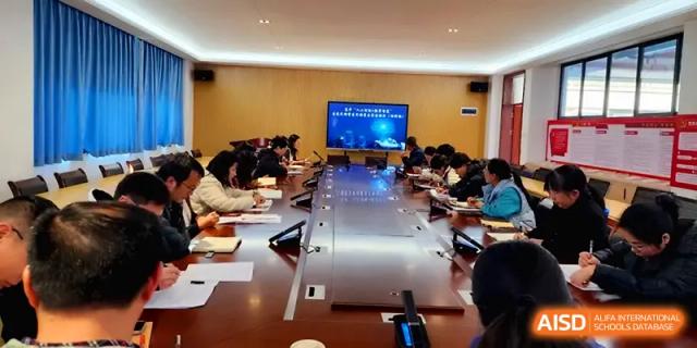 Faculty members participate in a formal conference around a large wooden table with a digital display at The Guandu Experimental School Affiliated To Shanghai Normal University.