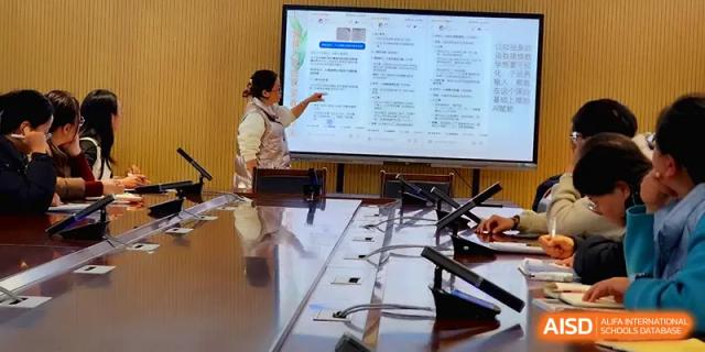 A teacher points to a detailed document projected on a screen in a professional meeting room at The Guandu Experimental School Affiliated To Shanghai Normal University.