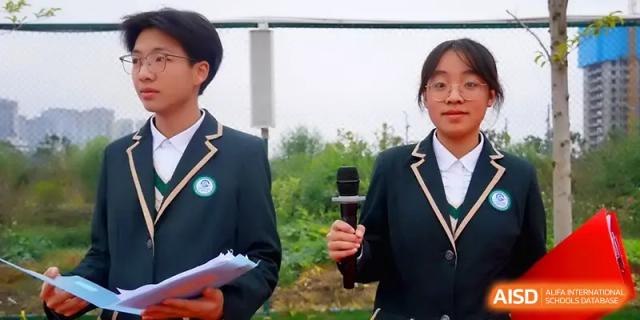 A student holds a microphone while speaking at an outdoor school gathering at The Guandu Experimental School Affiliated To Shanghai Normal University.
